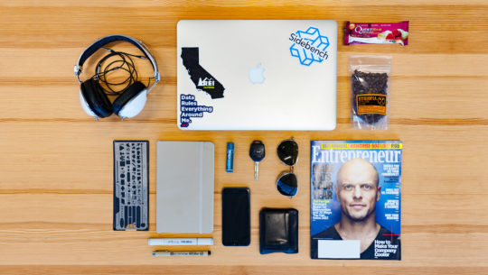 Image of entrepreneur magazine, macbook, notepad, sunglasses, wallet, iphone, earphones, quest bar